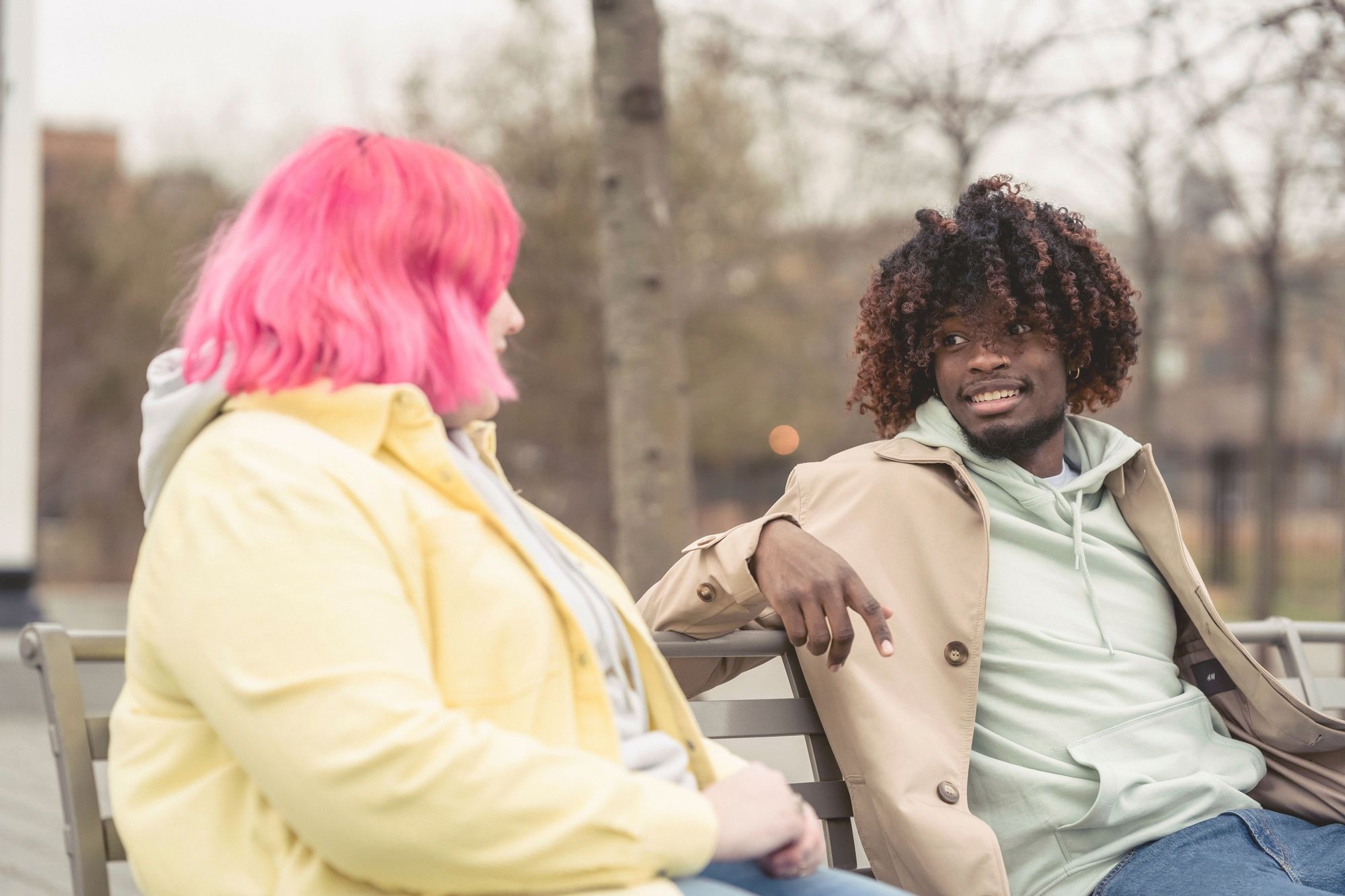 Two friends on a park bench, one in butter yellow talking, the other in mint listening.